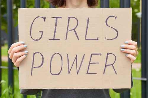 Žena drží kartonovou ceduli s nápisem Girls Power