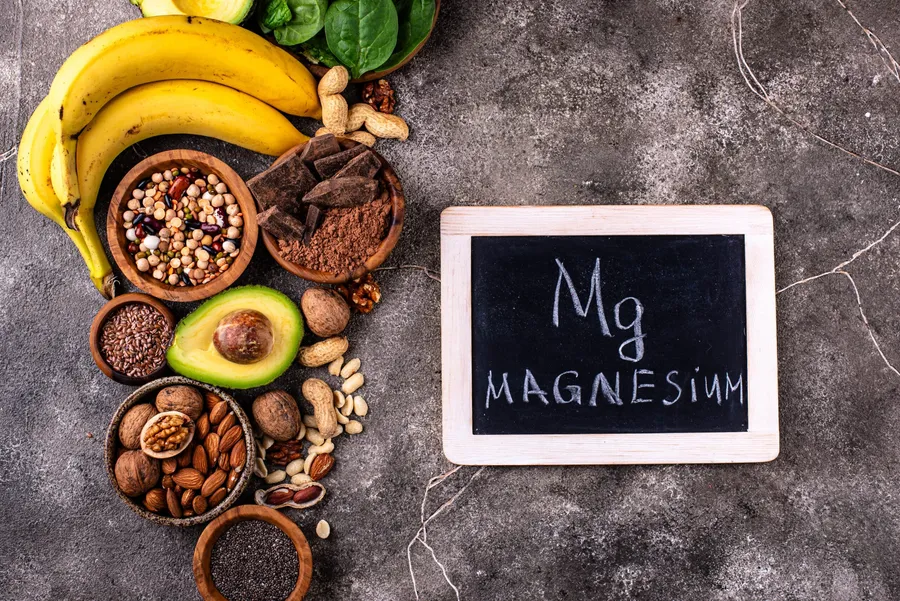 Potraviny bohaté na hořčík – ořechy, banány, avokádo, luštěniny a tabulka s nápisem Magnesium